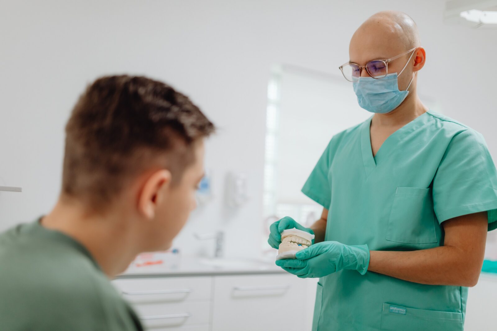 http://Dentist%20in%20scrubs%20explains%20dental%20procedure%20to%20a%20patient%20in%20an%20office%20setting.